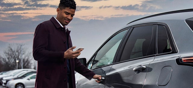 A man looking at his phone before entering a vehicle