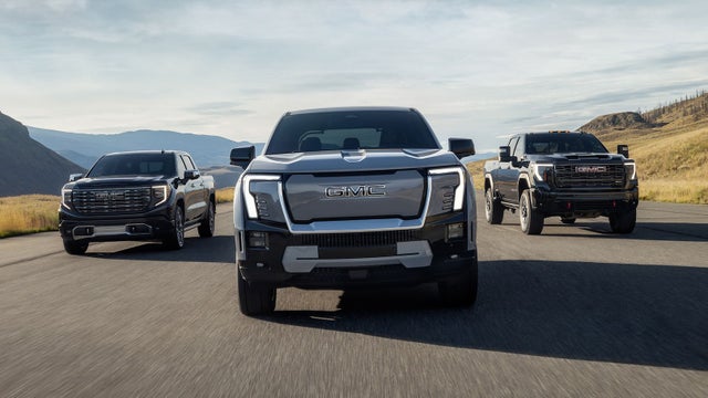 Three GMC Sierra Trucks Driving Down an Open Road