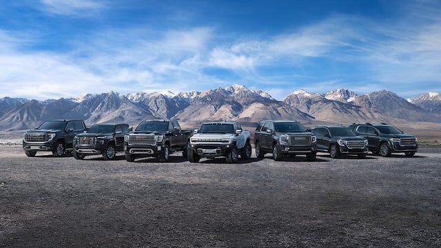 A Lineup of the GMC Vehicles parked in front of a mountain range